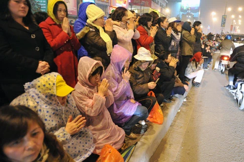 Cảnh đội mưa ngồi kín mít dài gần cây số tại tuyến đường Tây Sơn, gần Tổ đình Phúc Khánh lúc 19h tối 14/1 âm lịch Giao thông tắc nghẽn kéo dài trên tuyến đường này và một số phố giao nối Nhiều người che chắn tập thể bằng một tấm nylon dài, người chưa chuẩn bị đành ngồi đội mưa Tết Nguyên tiêu là ngày lễ thiêng đầu năm mới. Tục truyền, trong ngày rằm tháng Giêng, Đức Phật giáng lâm tại các chùa để chứng giám lòng thành của tín đồ Do đó ngày 14 hoặc chính rằm tháng Giêng, các đền, chùa trở nên quá tải. Tại Hà Nội, chùa Phúc Khánh nổi tiếng là nơi linh thiêng nhất nên thu hút rất đông người dân tới cầu phúc, cầu an Một trong những em bé theo mẹ đến ngồi hàng tiếng đồng hồ trên xe máy trong giá lạnh ngoài phố chờ làm lễ Dải phân cách tại lối lên cầu vượt Ngã Tư Sở cũng chật kín Một cô gái lặng lẽ mặc áo mưa, tay đi găng lầm rầm khấn vái Đứng tràn cả ra lòng đường, cậu thiếu niên này cũng chắp tay làm lễ như người lớn Hết giờ, ghế được giơ cao trên đầu trên đường về Niềm vui sau khi lễ bái thành công và được phát lộc của một người đàn ông Báo, giấy lót chỗ ngồi xả bừa bãi khiến tuyến đường tràn ngập rác