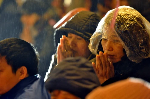 Cảnh đội mưa ngồi kín mít dài gần cây số tại tuyến đường Tây Sơn, gần Tổ đình Phúc Khánh lúc 19h tối 14/1 âm lịch Giao thông tắc nghẽn kéo dài trên tuyến đường này và một số phố giao nối Nhiều người che chắn tập thể bằng một tấm nylon dài, người chưa chuẩn bị đành ngồi đội mưa Tết Nguyên tiêu là ngày lễ thiêng đầu năm mới. Tục truyền, trong ngày rằm tháng Giêng, Đức Phật giáng lâm tại các chùa để chứng giám lòng thành của tín đồ Do đó ngày 14 hoặc chính rằm tháng Giêng, các đền, chùa trở nên quá tải. Tại Hà Nội, chùa Phúc Khánh nổi tiếng là nơi linh thiêng nhất nên thu hút rất đông người dân tới cầu phúc, cầu an Một trong những em bé theo mẹ đến ngồi hàng tiếng đồng hồ trên xe máy trong giá lạnh ngoài phố chờ làm lễ Dải phân cách tại lối lên cầu vượt Ngã Tư Sở cũng chật kín Một cô gái lặng lẽ mặc áo mưa, tay đi găng lầm rầm khấn vái Đứng tràn cả ra lòng đường, cậu thiếu niên này cũng chắp tay làm lễ như người lớn Hết giờ, ghế được giơ cao trên đầu trên đường về Niềm vui sau khi lễ bái thành công và được phát lộc của một người đàn ông Báo, giấy lót chỗ ngồi xả bừa bãi khiến tuyến đường tràn ngập rác