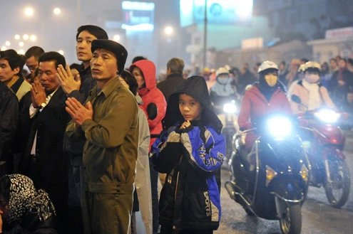 Cảnh đội mưa ngồi kín mít dài gần cây số tại tuyến đường Tây Sơn, gần Tổ đình Phúc Khánh lúc 19h tối 14/1 âm lịch Giao thông tắc nghẽn kéo dài trên tuyến đường này và một số phố giao nối Nhiều người che chắn tập thể bằng một tấm nylon dài, người chưa chuẩn bị đành ngồi đội mưa Tết Nguyên tiêu là ngày lễ thiêng đầu năm mới. Tục truyền, trong ngày rằm tháng Giêng, Đức Phật giáng lâm tại các chùa để chứng giám lòng thành của tín đồ Do đó ngày 14 hoặc chính rằm tháng Giêng, các đền, chùa trở nên quá tải. Tại Hà Nội, chùa Phúc Khánh nổi tiếng là nơi linh thiêng nhất nên thu hút rất đông người dân tới cầu phúc, cầu an Một trong những em bé theo mẹ đến ngồi hàng tiếng đồng hồ trên xe máy trong giá lạnh ngoài phố chờ làm lễ Dải phân cách tại lối lên cầu vượt Ngã Tư Sở cũng chật kín Một cô gái lặng lẽ mặc áo mưa, tay đi găng lầm rầm khấn vái Đứng tràn cả ra lòng đường, cậu thiếu niên này cũng chắp tay làm lễ như người lớn Hết giờ, ghế được giơ cao trên đầu trên đường về Niềm vui sau khi lễ bái thành công và được phát lộc của một người đàn ông Báo, giấy lót chỗ ngồi xả bừa bãi khiến tuyến đường tràn ngập rác