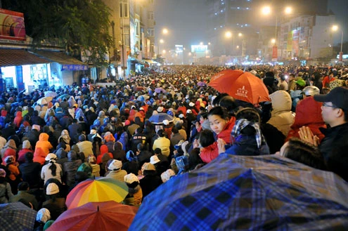 Cảnh đội mưa ngồi kín mít dài gần cây số tại tuyến đường Tây Sơn, gần Tổ đình Phúc Khánh lúc 19h tối 14/1 âm lịch Giao thông tắc nghẽn kéo dài trên tuyến đường này và một số phố giao nối Nhiều người che chắn tập thể bằng một tấm nylon dài, người chưa chuẩn bị đành ngồi đội mưa Tết Nguyên tiêu là ngày lễ thiêng đầu năm mới. Tục truyền, trong ngày rằm tháng Giêng, Đức Phật giáng lâm tại các chùa để chứng giám lòng thành của tín đồ Do đó ngày 14 hoặc chính rằm tháng Giêng, các đền, chùa trở nên quá tải. Tại Hà Nội, chùa Phúc Khánh nổi tiếng là nơi linh thiêng nhất nên thu hút rất đông người dân tới cầu phúc, cầu an Một trong những em bé theo mẹ đến ngồi hàng tiếng đồng hồ trên xe máy trong giá lạnh ngoài phố chờ làm lễ Dải phân cách tại lối lên cầu vượt Ngã Tư Sở cũng chật kín Một cô gái lặng lẽ mặc áo mưa, tay đi găng lầm rầm khấn vái Đứng tràn cả ra lòng đường, cậu thiếu niên này cũng chắp tay làm lễ như người lớn Hết giờ, ghế được giơ cao trên đầu trên đường về Niềm vui sau khi lễ bái thành công và được phát lộc của một người đàn ông Báo, giấy lót chỗ ngồi xả bừa bãi khiến tuyến đường tràn ngập rác