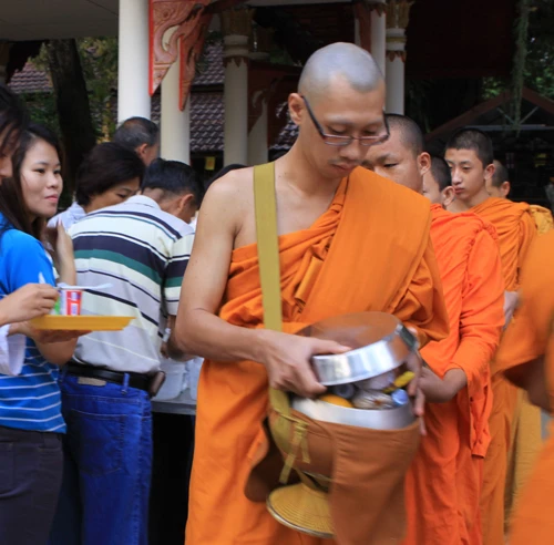 Cô Orathai Weingjai (bìa trái) vừa cúng dường xong cho bạn trai, nhà sư trẻ Suthee, mắt cứ mãi dõi theo... - Ảnh: Hồng Vân.