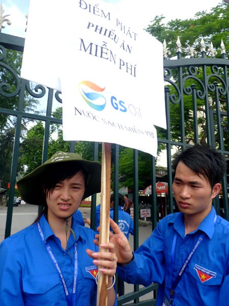 Các tình nguyện viên phát phiếu để nhận cơm (ảnh: Dân trí) Các tình nguyện viên phát phiếu để nhận cơm (ảnh: Dân trí)