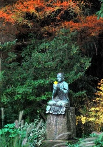 Một tượng Phật đặt dọc lối đi với bông hoa tươi trên tay - Ảnh: Trung Uyên