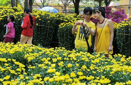 Các bạn trẻ thích thú chụp ảnh tại chợ hoa Tết ở Công viên 23-9, quận 1, TP.HCM - Ảnh: Minh Đức