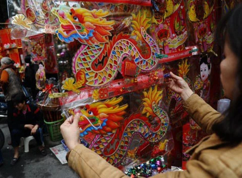 Một phụ nữ đang xem các vật trang trí có hình con rồng tại một gian hàng trên đường phố Hà Nội. Ảnh: AFP