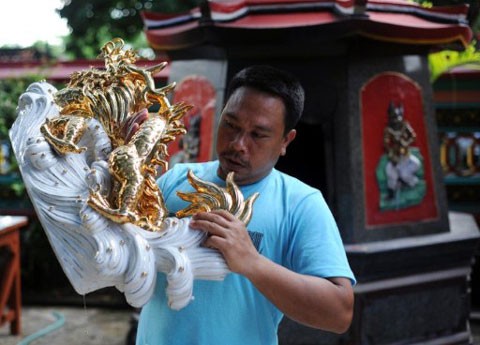 Người đàn ông ở đảo Bali, Indonesia, đang cầm một bức tượng rồng dát vàng, một vật trang trí để chuẩn bị đón chào năm mới theo lịch âm. Ảnh: AFP Người đàn ông ở đảo Bali, Indonesia, đang cầm một bức tượng rồng dát vàng, một vật trang trí để chuẩn bị đón chào năm mới theo lịch âm. Ảnh: AFP