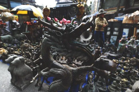 Bức tượng rồng bằng đồng được bày bán cùng nhiều đồ đồng khác tại một phiên chợ Tết ở Hà Nội. Ảnh: AFP