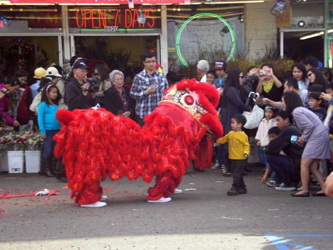 Một em bạo dạn tiến lại gần miệng chú lân, có lẽ để lì xì cho chú.