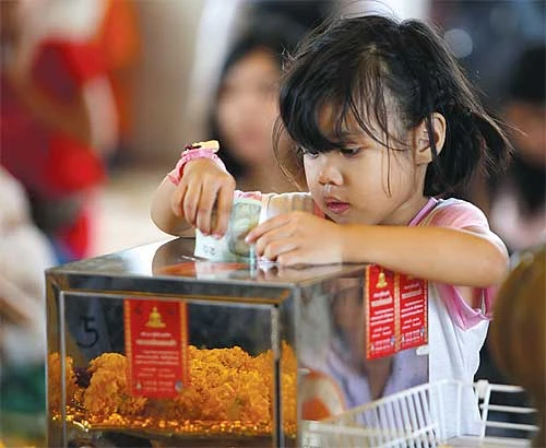 Phật tử Thái tổ chức Lễ Asarnha Bucha ảnh 3 Cô bé cúng d__ng trong hòm công __c t_i chùa Traimitr Withayaram (Bangkok).jpg
