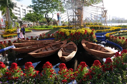 Sau những tuyến đường lớn như Đồng Khởi, Lê Duẩn, Lê Lợi, một số phố khác ở trung tâm thành phố cũng hoàn thành việc trang trí Tết. Đây là năm mà TP HCM có nhiều tuyến được thắp sáng bằng các dải đèn màu, theo từng chủ đề khác nhau. Thương xá Tax năm nay lấy màu hoa mai làm chủ đạo với ánh đèn đỏ, ấm vàng. Bên dưới là các trang trí Tết, từ 18h, rất đông người đến chụp ảnh và ngắm không khí xuân. Trong khi đó, từ các cửa hiệu lớn... ... đến các trung tâm thương mại, khách sạn bắt đầu trang trí bằng ánh sáng đủ màu. Đường hoa Nguyễn Huệ đang bước vào những ngày cuối cùng trước khi khai mạc sáng 27 tháng Chạp. Các biểu tượng năm rắn và quê hương đất nước đã gần hoàn thành. Những công nhân đang tưới các giò hoa treo cao. Mỗi chủ đề trên con đường hoa năm nay được dàn dựng bằng các hình ảnh mang cảnh sắc quen thuộc của Việt Nam. Rặng tre, ruộng lúa và khóm hoa xuất hiện giữa đường. Nhiều tuyến phố trung tâm thành phố được trang trí bằng đủ các loại hoa sặc sỡ. Tượng đài Hồ Chủ tịch trước UBND thành phố với sen chủ đạo và các cánh hoa màu sắc khác nhau. Các con thuyền hoa bên cạnh hồ Bán nguyệt, quận 7. Các hội chợ, lễ hội hoa đã diễn ra từ ngày 23 tháng Chạp. Năm nay, hoa từ các tỉnh miền Tây và phía Bắc chuyển về nhiều, mức giá vừa phải. Trong những ngày đầu mở cửa, lượng khách vãn cảnh nhiều, nhưng người mua ít.