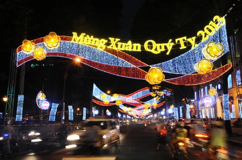 Sau những tuyến đường lớn như Đồng Khởi, Lê Duẩn, Lê Lợi, một số phố khác ở trung tâm thành phố cũng hoàn thành việc trang trí Tết. Đây là năm mà TP HCM có nhiều tuyến được thắp sáng bằng các dải đèn màu, theo từng chủ đề khác nhau. Thương xá Tax năm nay lấy màu hoa mai làm chủ đạo với ánh đèn đỏ, ấm vàng. Bên dưới là các trang trí Tết, từ 18h, rất đông người đến chụp ảnh và ngắm không khí xuân. Trong khi đó, từ các cửa hiệu lớn... ... đến các trung tâm thương mại, khách sạn bắt đầu trang trí bằng ánh sáng đủ màu. Đường hoa Nguyễn Huệ đang bước vào những ngày cuối cùng trước khi khai mạc sáng 27 tháng Chạp. Các biểu tượng năm rắn và quê hương đất nước đã gần hoàn thành. Những công nhân đang tưới các giò hoa treo cao. Mỗi chủ đề trên con đường hoa năm nay được dàn dựng bằng các hình ảnh mang cảnh sắc quen thuộc của Việt Nam. Rặng tre, ruộng lúa và khóm hoa xuất hiện giữa đường. Nhiều tuyến phố trung tâm thành phố được trang trí bằng đủ các loại hoa sặc sỡ. Tượng đài Hồ Chủ tịch trước UBND thành phố với sen chủ đạo và các cánh hoa màu sắc khác nhau. Các con thuyền hoa bên cạnh hồ Bán nguyệt, quận 7. Các hội chợ, lễ hội hoa đã diễn ra từ ngày 23 tháng Chạp. Năm nay, hoa từ các tỉnh miền Tây và phía Bắc chuyển về nhiều, mức giá vừa phải. Trong những ngày đầu mở cửa, lượng khách vãn cảnh nhiều, nhưng người mua ít.