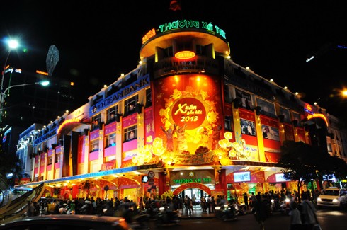 Sau những tuyến đường lớn như Đồng Khởi, Lê Duẩn, Lê Lợi, một số phố khác ở trung tâm thành phố cũng hoàn thành việc trang trí Tết. Đây là năm mà TP HCM có nhiều tuyến được thắp sáng bằng các dải đèn màu, theo từng chủ đề khác nhau. Thương xá Tax năm nay lấy màu hoa mai làm chủ đạo với ánh đèn đỏ, ấm vàng. Bên dưới là các trang trí Tết, từ 18h, rất đông người đến chụp ảnh và ngắm không khí xuân. Trong khi đó, từ các cửa hiệu lớn... ... đến các trung tâm thương mại, khách sạn bắt đầu trang trí bằng ánh sáng đủ màu. Đường hoa Nguyễn Huệ đang bước vào những ngày cuối cùng trước khi khai mạc sáng 27 tháng Chạp. Các biểu tượng năm rắn và quê hương đất nước đã gần hoàn thành. Những công nhân đang tưới các giò hoa treo cao. Mỗi chủ đề trên con đường hoa năm nay được dàn dựng bằng các hình ảnh mang cảnh sắc quen thuộc của Việt Nam. Rặng tre, ruộng lúa và khóm hoa xuất hiện giữa đường. Nhiều tuyến phố trung tâm thành phố được trang trí bằng đủ các loại hoa sặc sỡ. Tượng đài Hồ Chủ tịch trước UBND thành phố với sen chủ đạo và các cánh hoa màu sắc khác nhau. Các con thuyền hoa bên cạnh hồ Bán nguyệt, quận 7. Các hội chợ, lễ hội hoa đã diễn ra từ ngày 23 tháng Chạp. Năm nay, hoa từ các tỉnh miền Tây và phía Bắc chuyển về nhiều, mức giá vừa phải. Trong những ngày đầu mở cửa, lượng khách vãn cảnh nhiều, nhưng người mua ít.