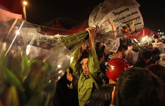 Một người đàn ông giơ hoa lên trên đầu tìm cách thoát khỏi đám đông.