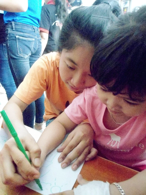 Anh 4 Ban Phuong Nghi (ao cam) dang cam tay em nho ve tranh.jpg