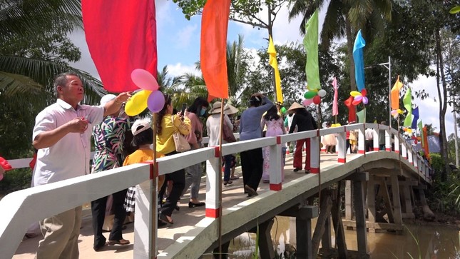 Khánh thành cầu bê-tông, tặng quà đến hộ nghèo ảnh 1 Người dân và trẻ em phấn khởi qua cầu.jpg