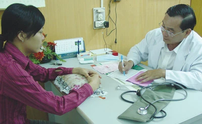 Lương y Nguyễn Viết Xô, Trưởng phòng khám từ thiện Tuệ Tĩnh Đường đang kê đơn thuốc cho bệnh nhân. Ảnh: Trần Đỗ Cẩm