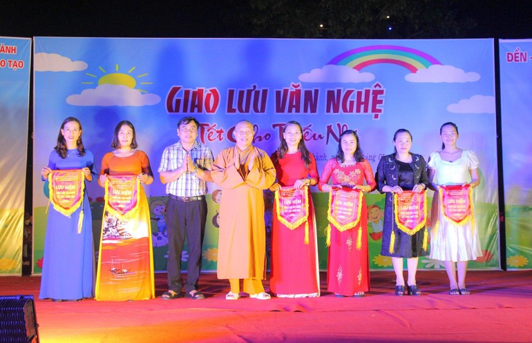 Thượng tọa Thích Thông Kiên và lãnh đạo huyện Yên Thành tặng cờ lưu niệm cho các đơn vị trường học tham dự chương trình văn nghệ