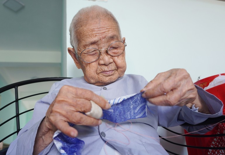 Mệ Huệ ở tuổi 101 vẫn tỉ mẫn may gối trái dựa cung đình để lưu giữ nghề truyền thống - Ảnh: Như Danh/Báo Giác Ngộ