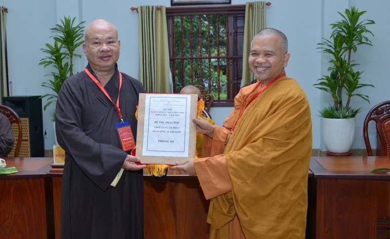 Thượng tọa Thích Phước Đạt đại diện Hội đồng tuyển sinh trao bộ đề thi được niêm phong đến Thượng tọa Thích Giác Hoàng, Tổng Giám thị Hội đồng coi thi