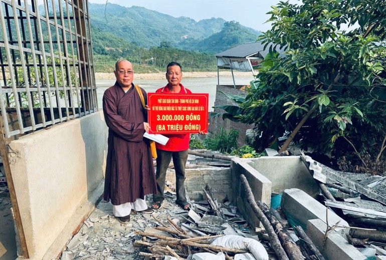 Thượng tọa Thích Đạt Đức trao bảng tượng trưng số tiền hỗ trợ cho các hộ gia đình có nhà bị sạt lở nặng, phải di dời