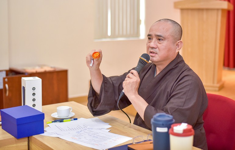 Thượng tọa Thích Tâm Hải giới thiệu biểu trưng (logo) chính thức của sự kiện Kỷ niệm 50 năm Báo Giác Ngộ ra số đầu tiên qua sản phẩm pin - Ảnh: Quảng Đạo/BGN