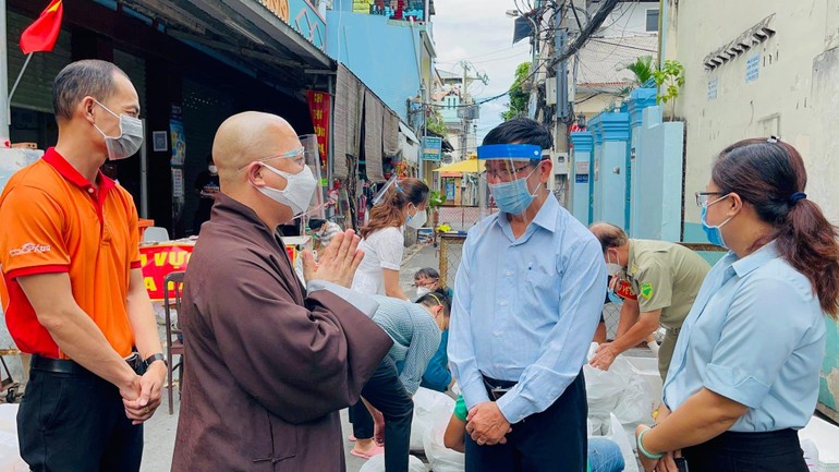 Thượng tọa Thích Trí Thông, Phó trụ trì chùa Viên Giác trao đổi với cán bộ khu cách ly để giúp đỡ người dân khó khăn - Ảnh: V.Gi