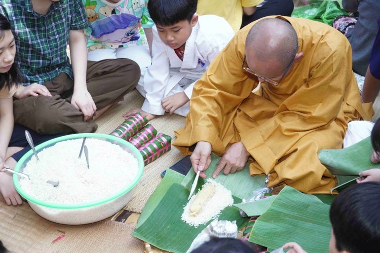 Đại đức Thích Thiện Hưng, trụ trì chùa Tam Bảo hướng dẫn gói bánh tét Tết cho các em thiếu nhi