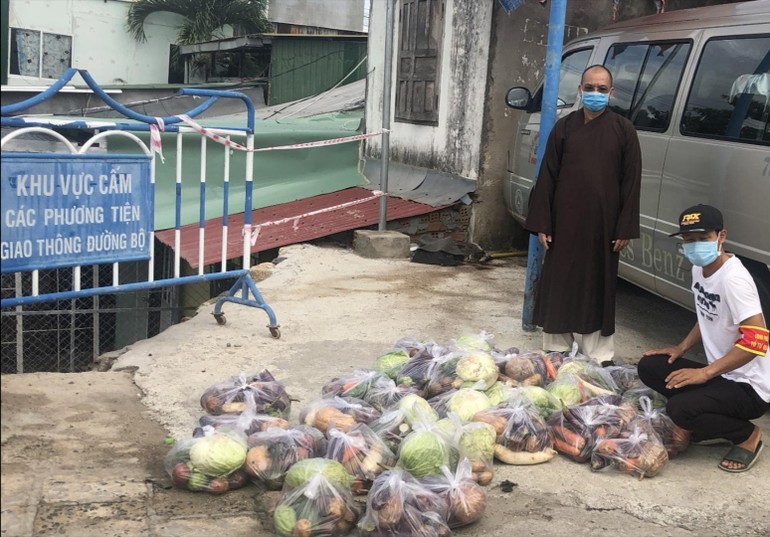 Thượng tọa Thích Huệ Giáo trao các phần quà trao đến người dân khu phong tỏa 