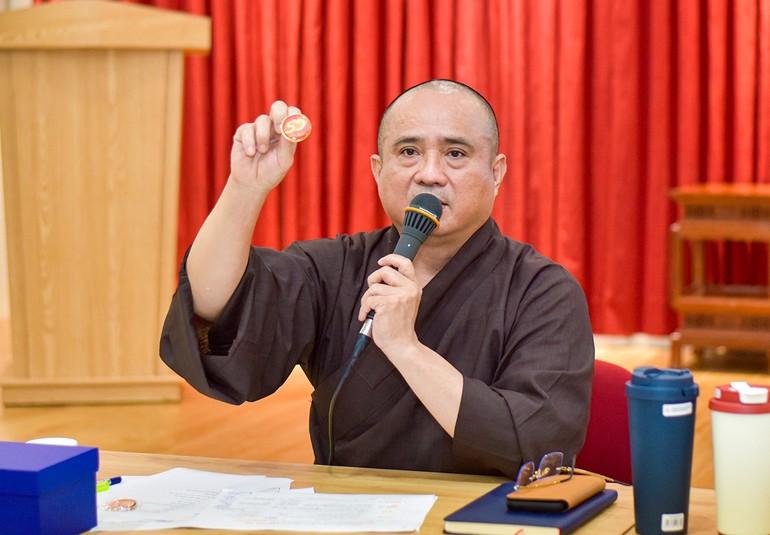 Thượng tọa Thích Tâm Hải giới thiệu biểu trưng (logo) chính thức của sự kiện Kỷ niệm 50 năm Báo Giác Ngộ ra số đầu tiên qua sản phẩm pin - Ảnh: Quảng Đạo/BGN