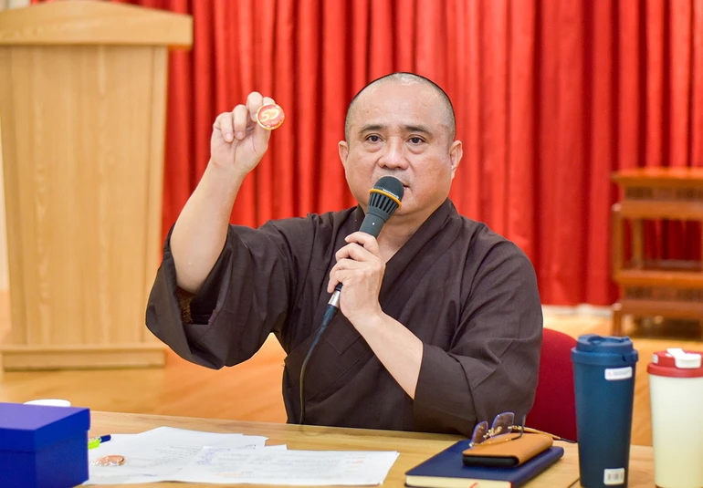 Thượng tọa Thích Tâm Hải giới thiệu biểu trưng (logo) chính thức của sự kiện Kỷ niệm 50 năm Báo Giác Ngộ ra số đầu tiên qua sản phẩm pin - Ảnh: Quảng Đạo/BGN