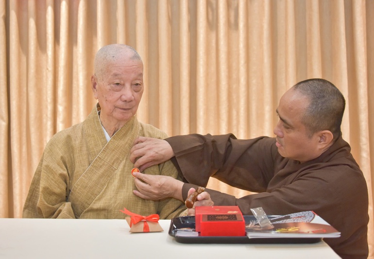 Thượng tọa Thích Tâm Hải, Tổng Biên tập Báo Giác Ngộ đương nhiệm đeo phù hiệu 50 năm Báo Giác Ngộ lên thông y của Đức Pháp chủ GHPGVN tại trụ sở tòa soạn chiều 30-12-2025 - Ảnh: Quảng Đạo