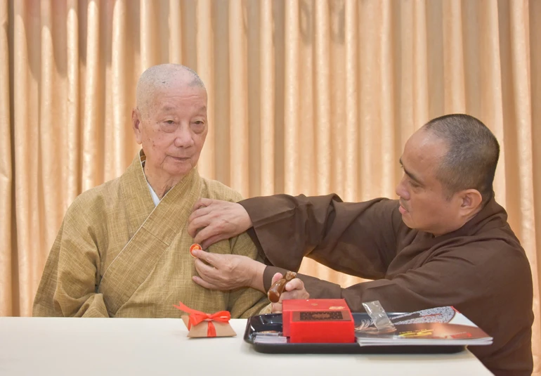 Thượng tọa Thích Tâm Hải, Tổng Biên tập Báo Giác Ngộ đương nhiệm đeo phù hiệu 50 năm Báo Giác Ngộ lên thông y của Đức Pháp chủ GHPGVN tại trụ sở tòa soạn chiều 30-12-2025 - Ảnh: Quảng Đạo