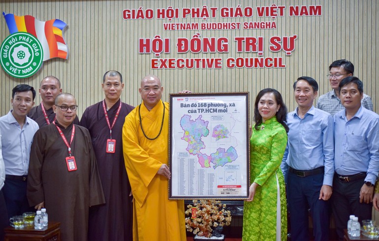 Bà Nguyễn Thanh Xuân tặng bản đồ 168 phường - xã TP.HCM đến Thượng tọa Thích Phước Nguyên - Ảnh: Quảng Đạo/BGN
