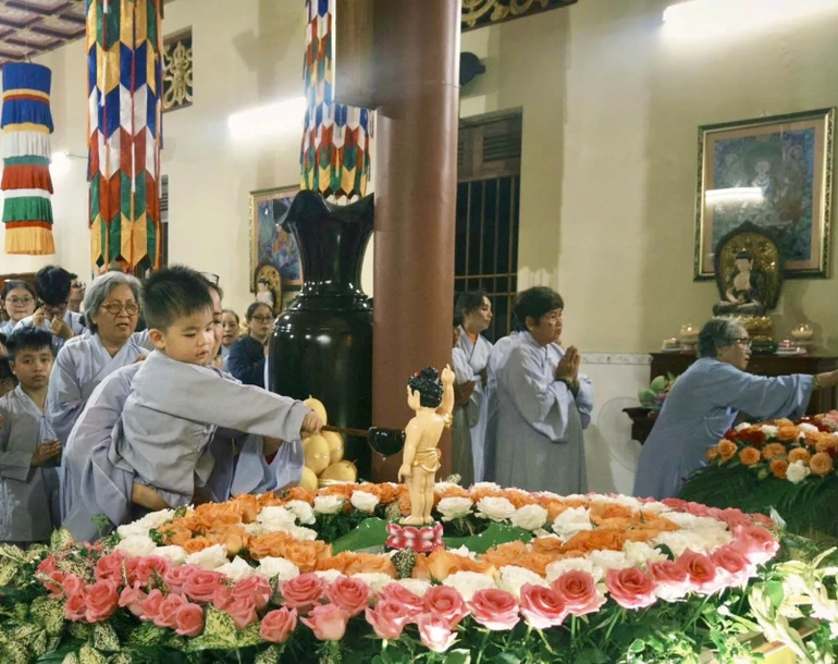 Em thơ được phụ huynh ẳm trên tay để Tắm Phật trong niềm háo hức
