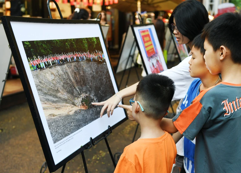 Các em thơ chăm chú xem, tìm hiểu lịch sử tại triển lãm ảnh “Hành trình về nguồn”