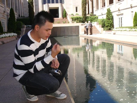 Tác giả  đang cầu nguyện bỏ đồng tiền xuống hồ trước Bảo tàng chiến tranh tại thủ đô Canberra của Úc