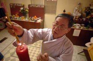 Bác Phạm Lịch đang đốt nhang cúng Phật tại chùa Cát Tường.