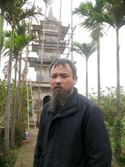 Hoạ sĩ Phan Cẩm Thượng bên ngọn Tháp Bút đang được anh tham gia trùng tu.