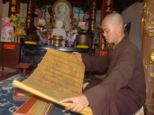 Đại đức Thích Như Tiến - trụ trì chùa Hoa Sơn giới thiệu các sắc phong. (Ảnh: Đoàn Hữu Trung/Vietnam+)