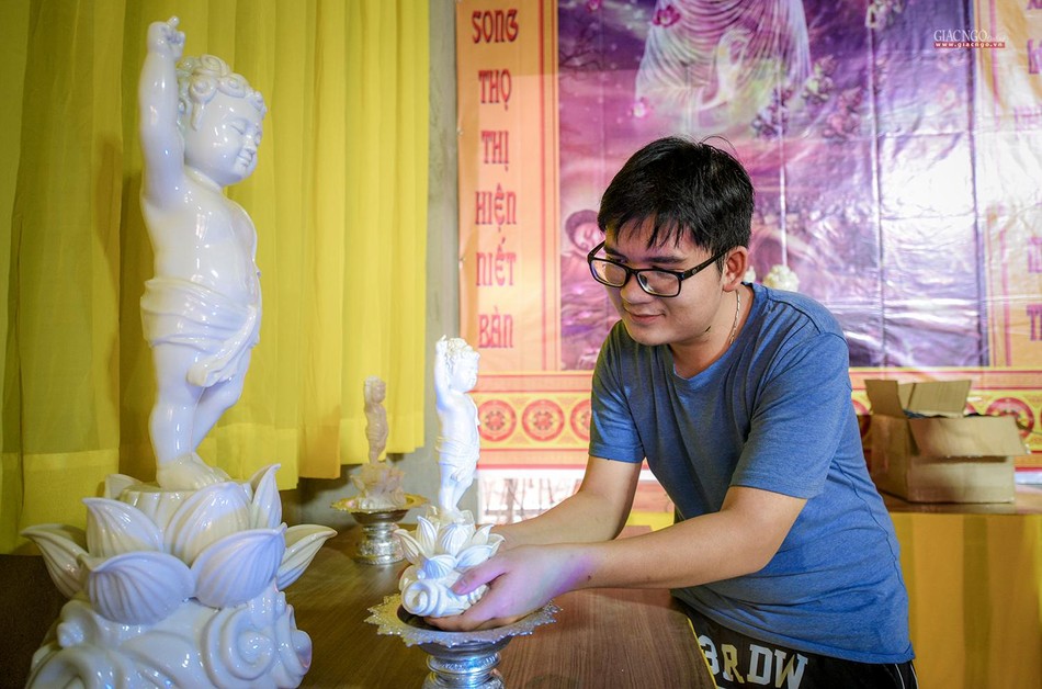 Một bạn trẻ tên Đạt (pháp danh Phước Tâm, 20 tuổi) kính cẩn đặt tôn tượng Phật đản sanh lên bệ thờ Một bạn trẻ tên Đạt (pháp danh Phước Tâm, 20 tuổi) kính cẩn đặt tôn tượng Phật đản sanh lên bệ thờ