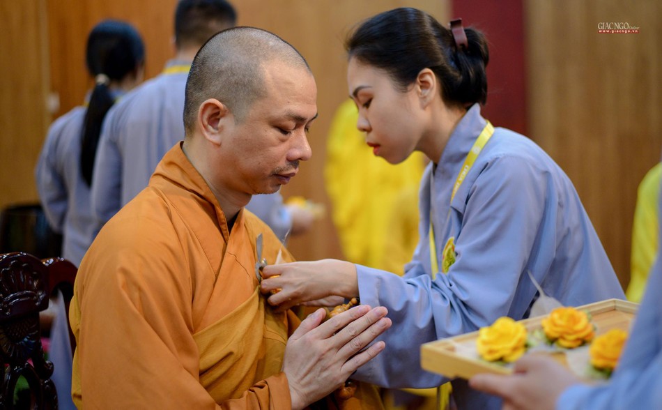 Một Phật tử kính cẩn cài bông hoa hồng lên ngực một chư Tăng