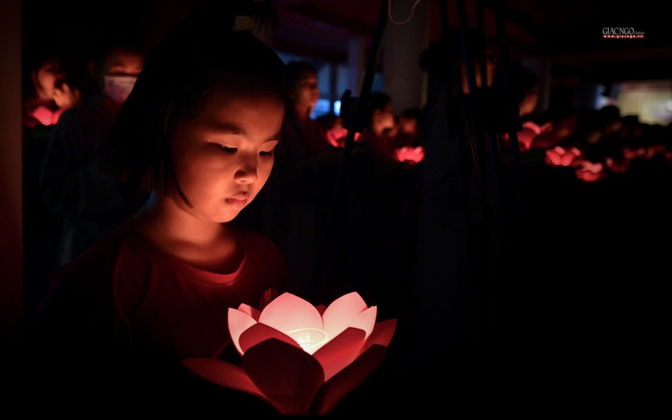 Một em bé được mẹ hướng dẫn thắp nến tưởng niệm