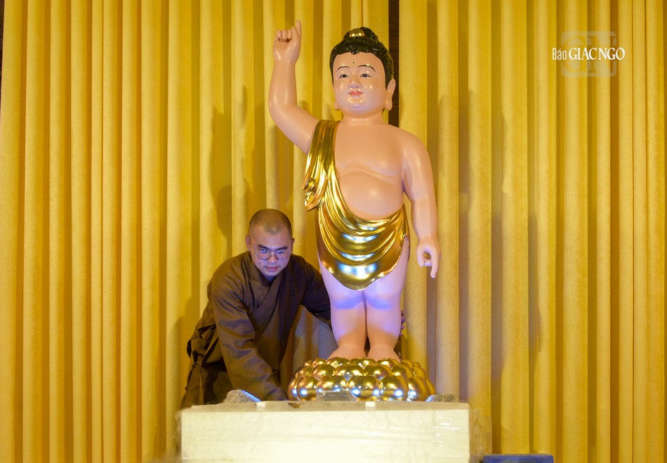 Trong ảnh là một vị tu sĩ đang điều chỉnh tôn tượng Đức Phật đản sinh tại lễ đài chùa Phước Duyên