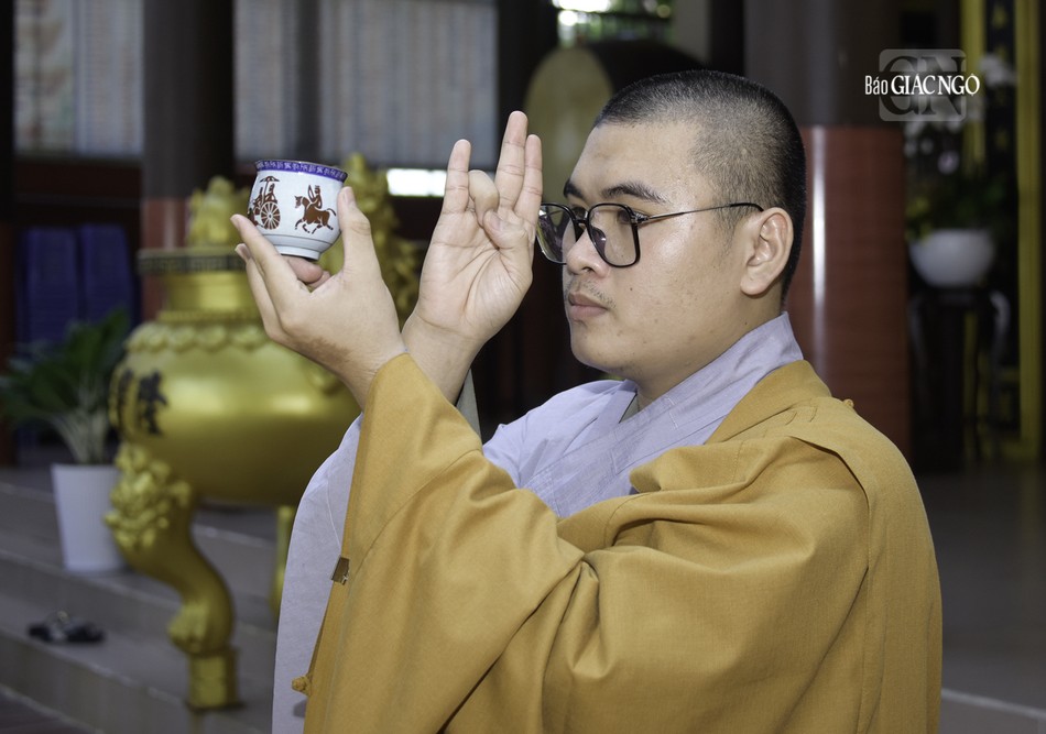 Một vị Sa-di thực hiện nghi thức cúng đại bàng trước phần thọ thực của chư Tăng