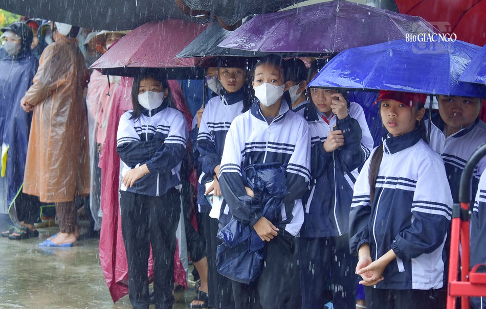 Các em học sinh đội mưa chờ nhận quà