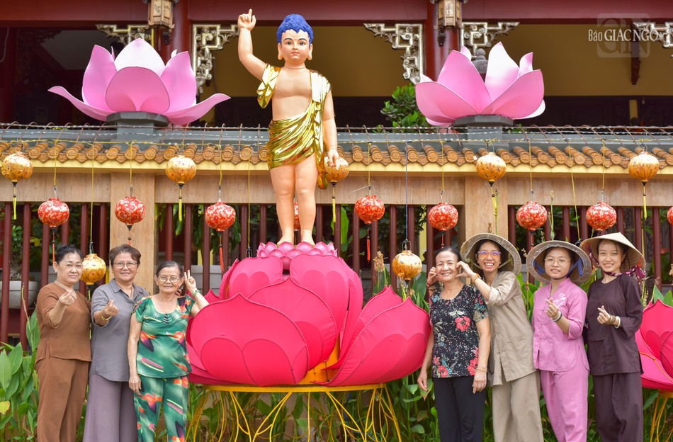 Các tình nguyện viên, Phật tử chụp hình bên tôn tượng Đức Phật đản sinh trong khuôn viên chùa