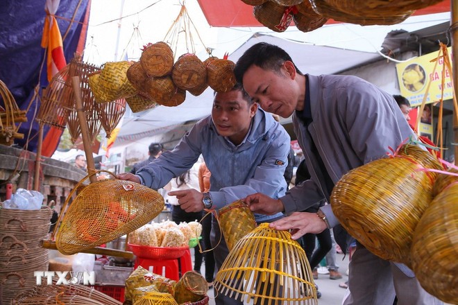 Du khách tham quan, lựa chọn mua những kỷ vật nghề nông để lấy may mắn khi đi chợ Viềng. (Ảnh: Công Luật/TTXVN)