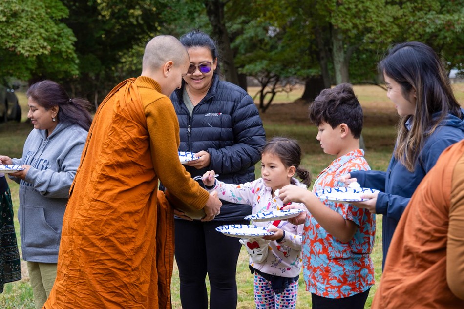Các em nhỏ theo sự hướng dẫn của cha mẹ thành tâm dâng phẩm vật lên chư Tăng Ni