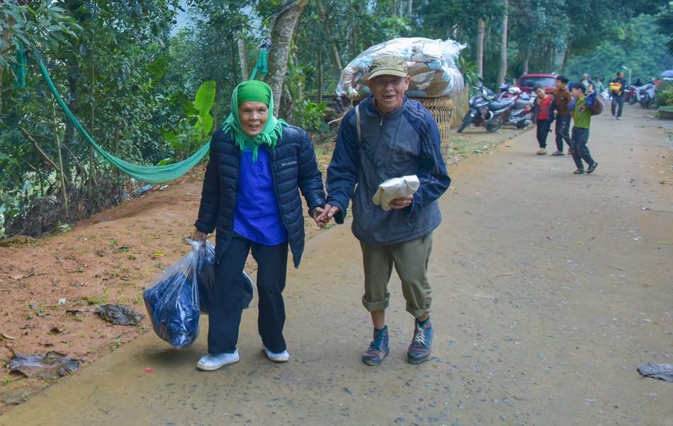 Sau khi nhận quà, vợ chồng ông bà Nùng Thị Sùng và Nguyễn Văn Mìn nắm tay nhau bước vội trên con dốc dẫn lên nương