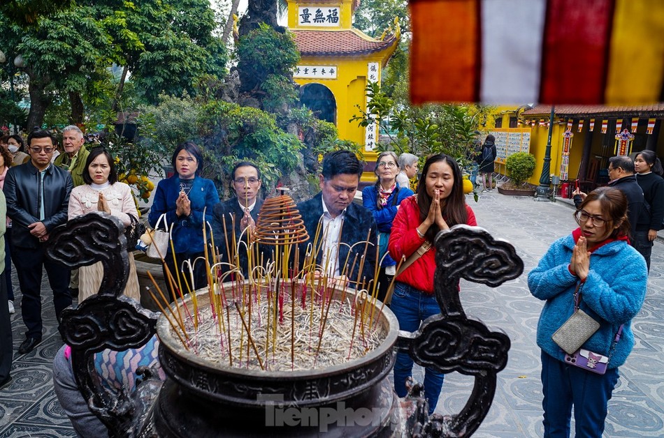 Người dân và du khách đến thắp hương tại chùa Trấn Quốc (Q.Tây Hồ), khấn nguyện những điều tốt đẹp sẽ đến trong năm mới - Ảnh: Đức Nguyễn